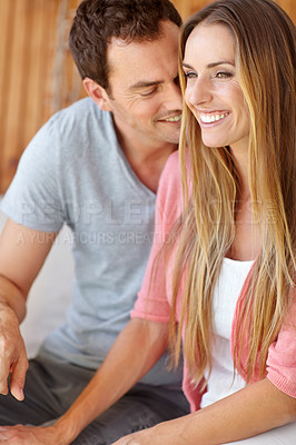 Buy stock photo A handsome young husband lovingly looking at his wife while they sit on the couch together