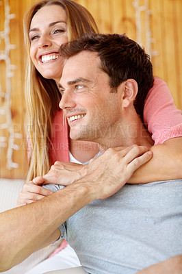 Buy stock photo A happy young couple sitting on the couch embracing lovingly