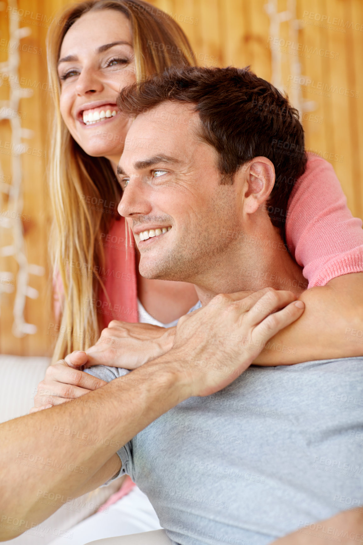 Buy stock photo A happy young couple sitting on the couch embracing lovingly