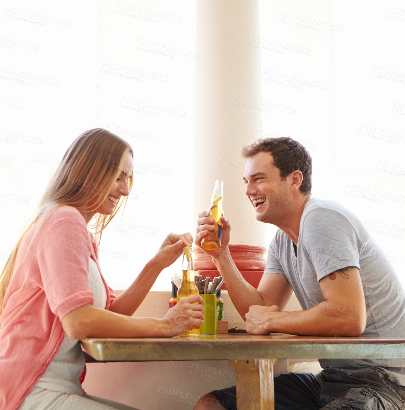 Buy stock photo A happy young couple enjoying an alcoholic drink in a restaurant