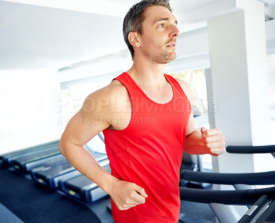 Buy stock photo A handsome young man exercising on a treadmill at the gym