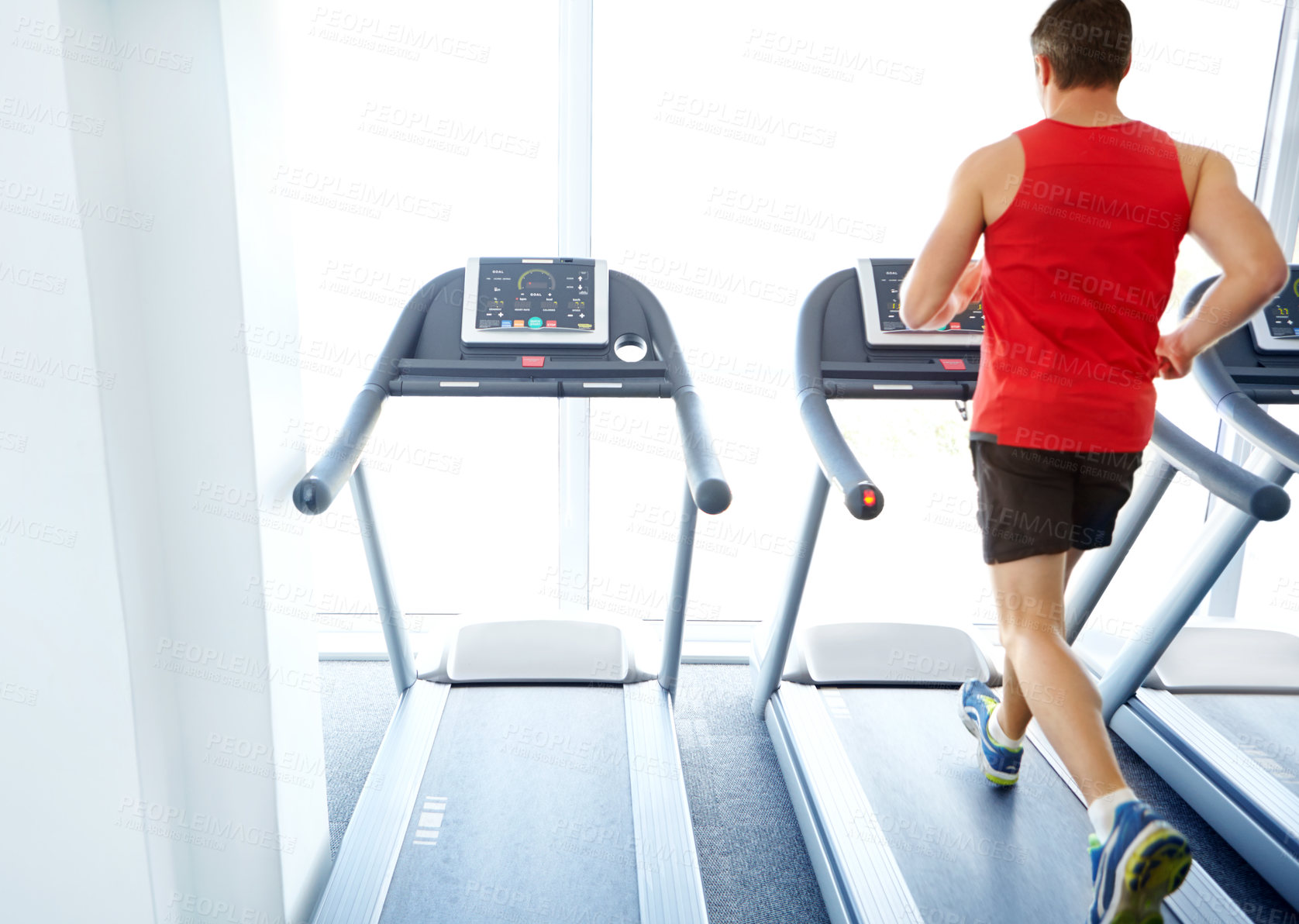 Buy stock photo A handsome young man exercising on a treadmill at the gym