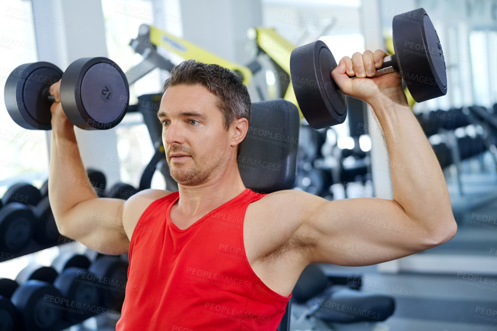 Buy stock photo A handsome young man doing weight training at the gym