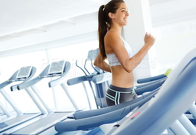 Buy stock photo A beautiful young woman exercising on a treadmill at the gym