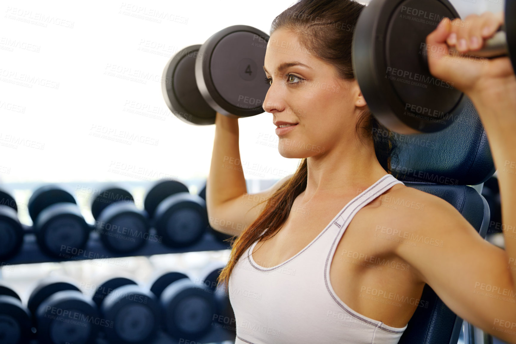 Buy stock photo A beautiful young woman exercising with weights at the gym