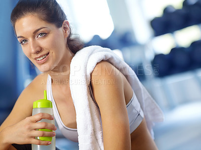 Buy stock photo A beautiful young woman sitting at the gym taking a break and having a drink of water