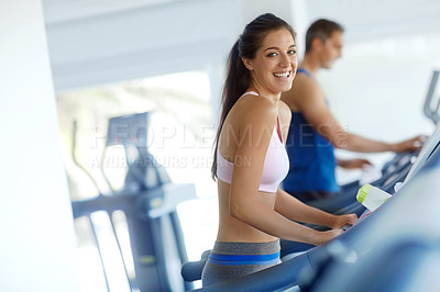 Buy stock photo A young man and woman exercising on treadmills at the gym