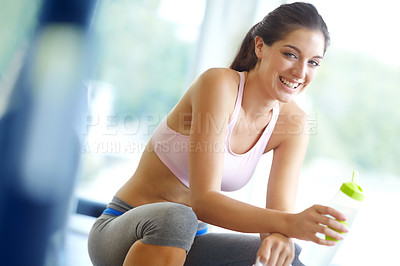 Buy stock photo A beautiful young woman sitting at the gym taking a break and having a drink of water