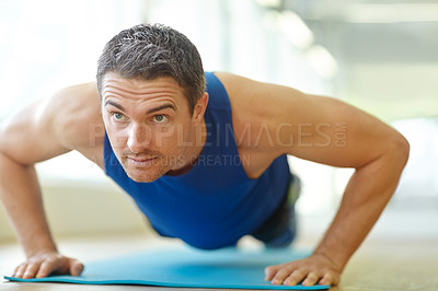 Buy stock photo A handsome man doing push-ups at the gym