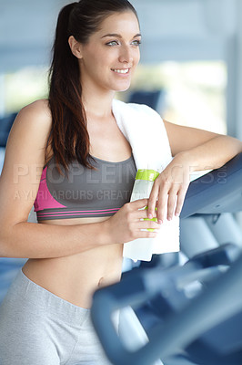 Buy stock photo A beautiful young woman leaning on a treadmill holding a water bottle at the gym