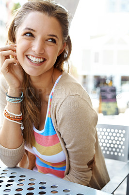 Buy stock photo A beautiful young woman smilng happily while sitting at a sidewalk cafe in the city