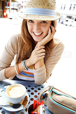 Buy stock photo A happy young woman smiling at the camera while sitting at a sidewalk coffee shop in the city