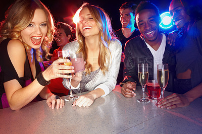 Buy stock photo A group of friends smiling at the camera while they enjoy drinks in a nightclub