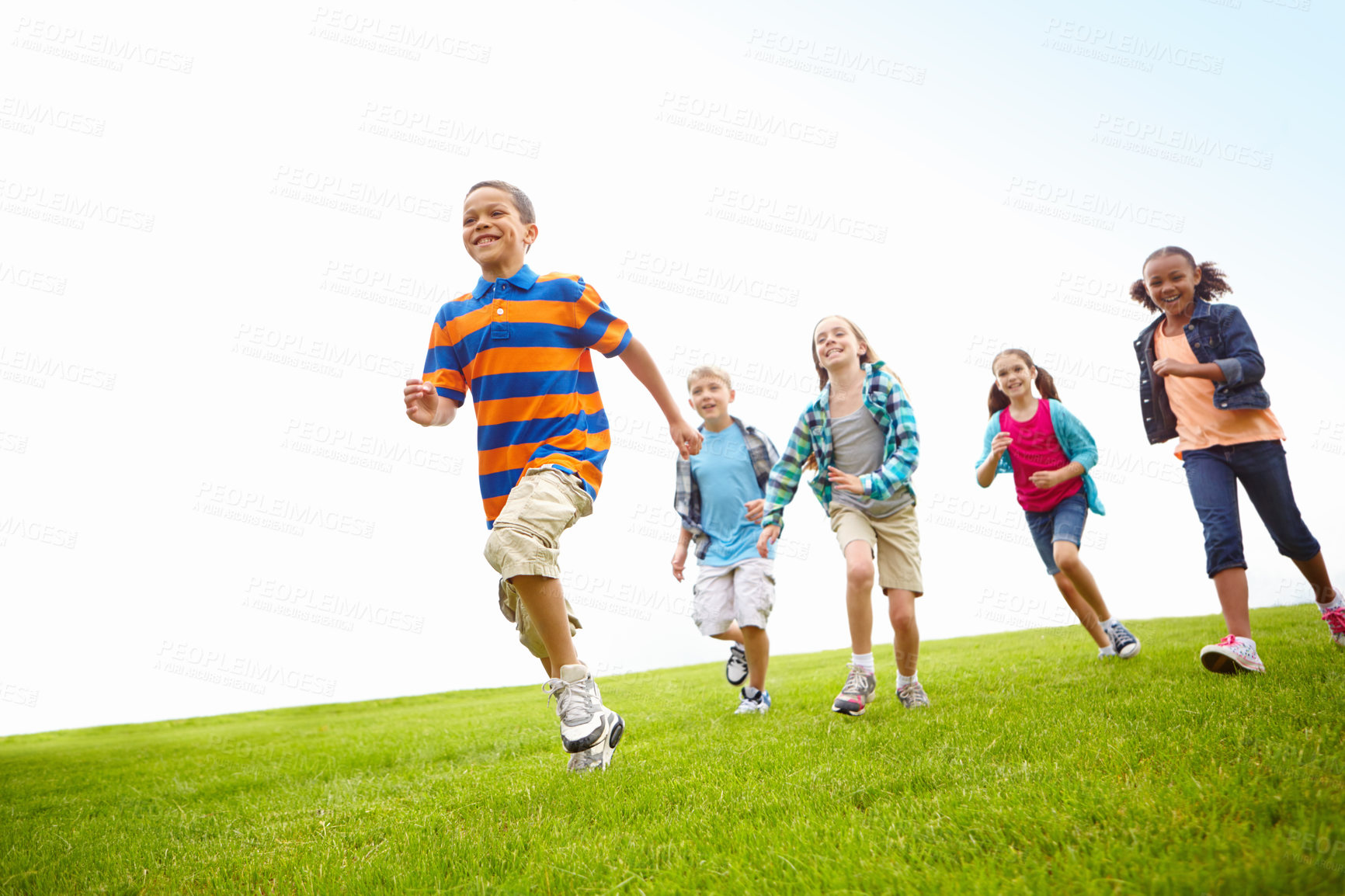 Buy stock photo Group of energetic children running through a park together