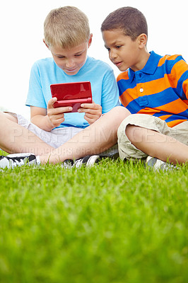 Buy stock photo Two fascinated little boys holding a nintendo gaming console and playing on it