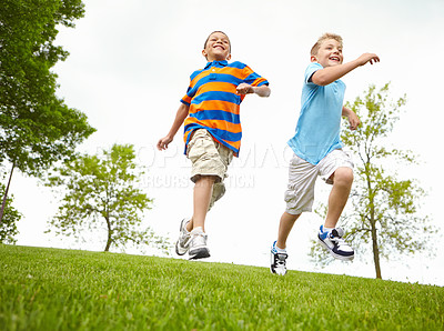 Buy stock photo Two little boys running through a park together and having fun