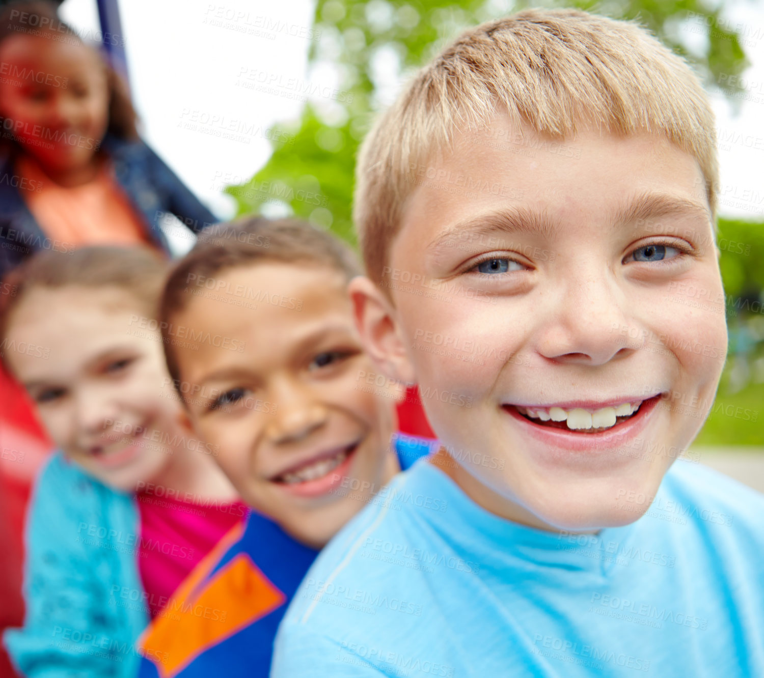 Buy stock photo A happy group of multi-ethnic children sitting happily on a slide in a play park