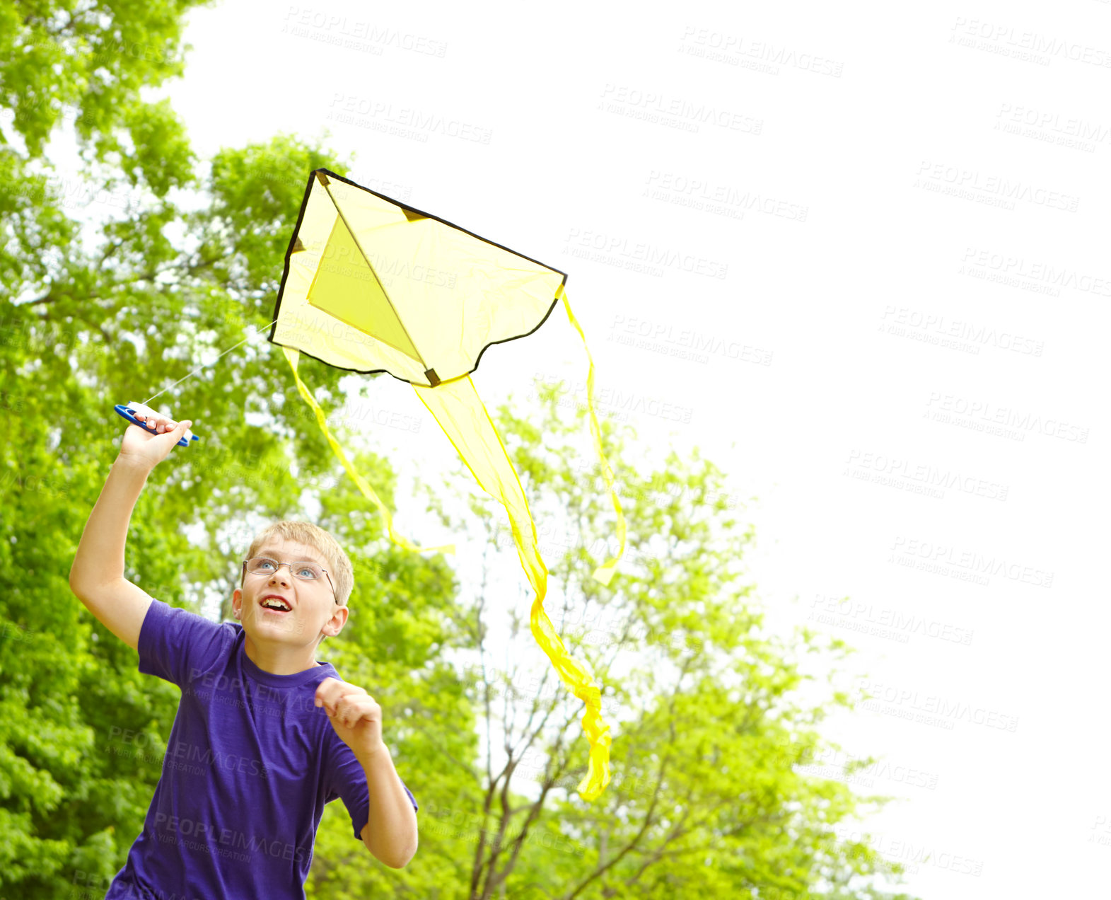 Buy stock photo A happy young boy flying a kite outside in a park