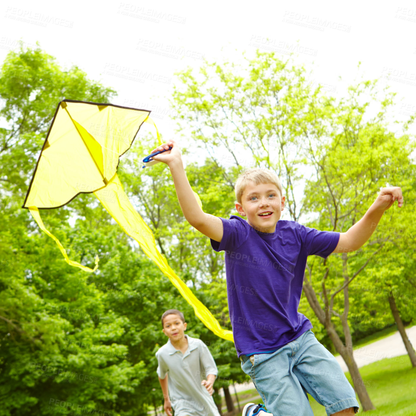 Buy stock photo A happy young boy flying a kite outside in a park