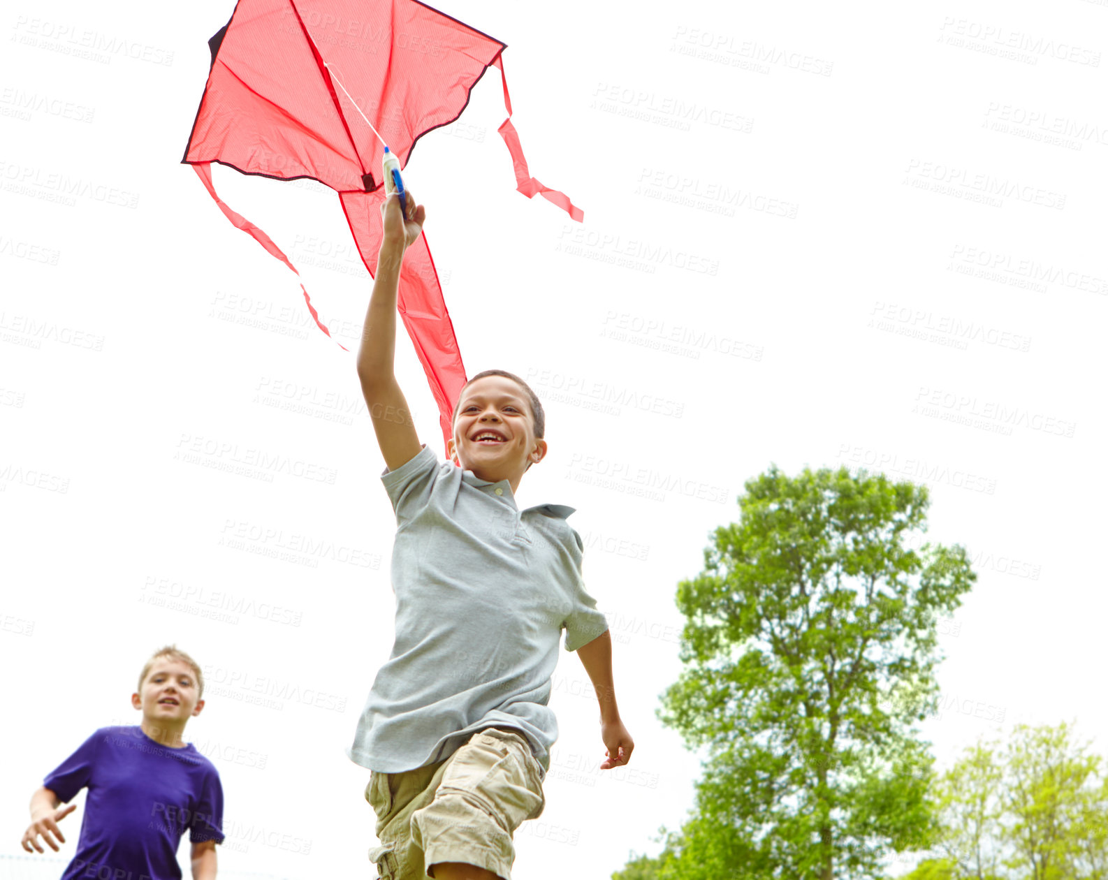 Buy stock photo A happy young boy flying a kite outside in a park