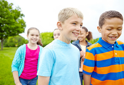 Buy stock photo Two young boys standing outside smiling at the camera with their friends behind them