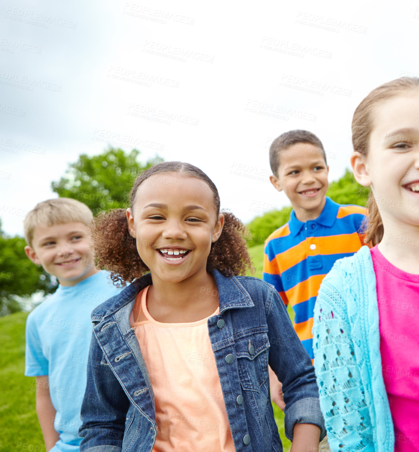 Buy stock photo A multi-ethnic group of kids standing outside in a park