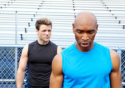 Buy stock photo Cropped shot of two male runners wearing sports gear and standing together at the track
