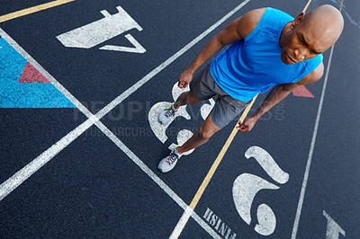 Buy stock photo High angle view of a male runner with a focused expression getting ready to run