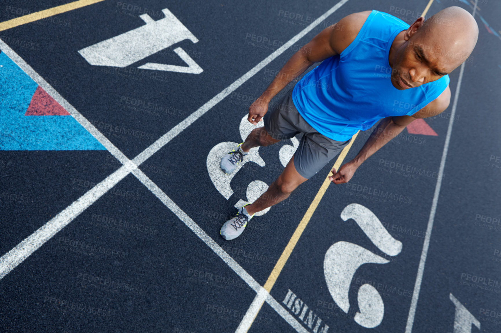 Buy stock photo High angle view of a male runner with a focused expression getting ready to run