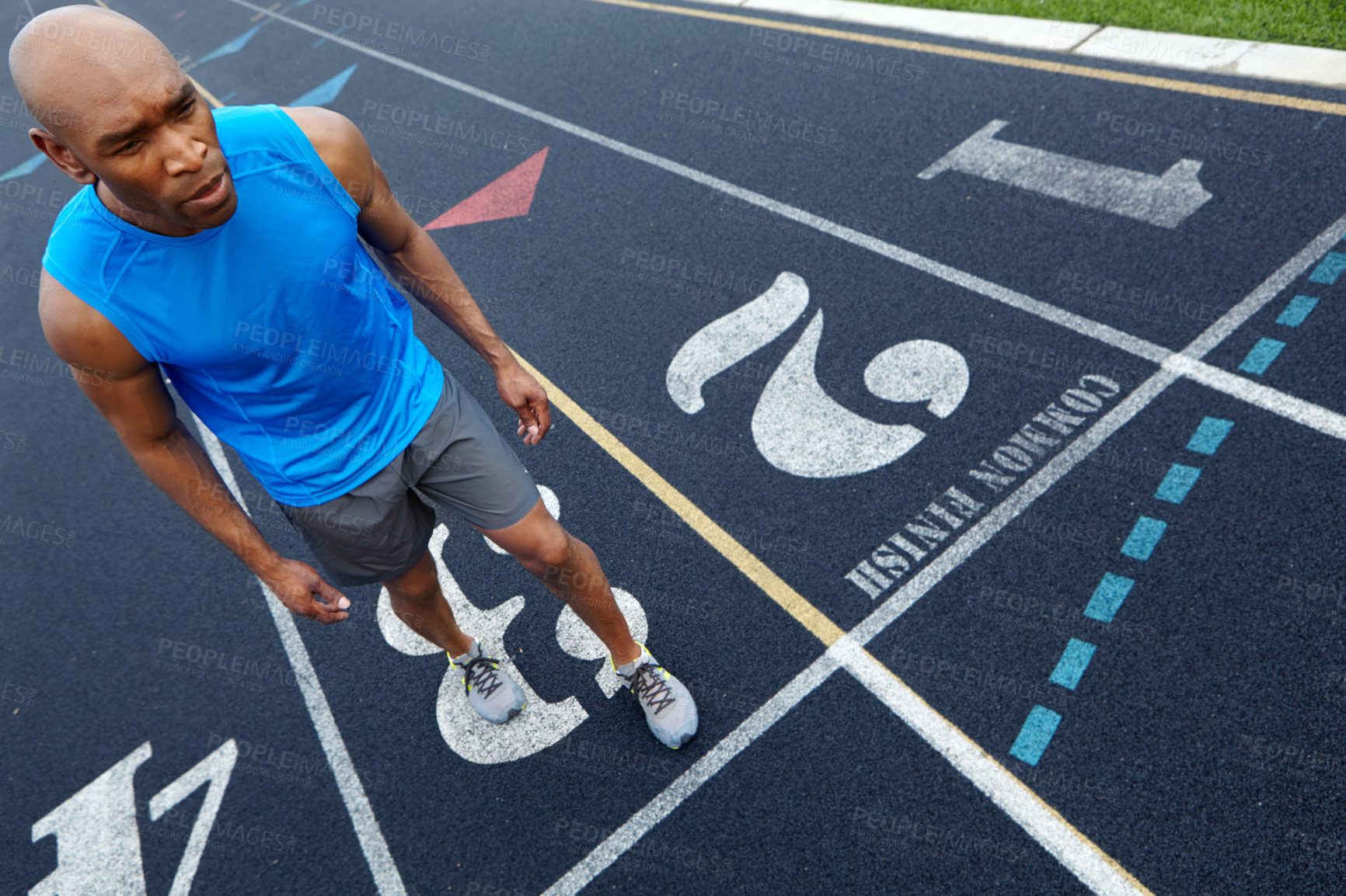 Buy stock photo High angle view of a male runner with a look of concentration in position to start the race