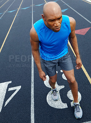 Buy stock photo High angle view of a male runner with a focused expression at the starting position