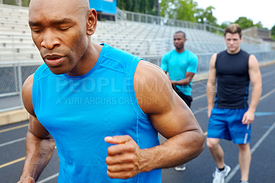 Buy stock photo Close up of a male runner with competitors in the background warming up for the race