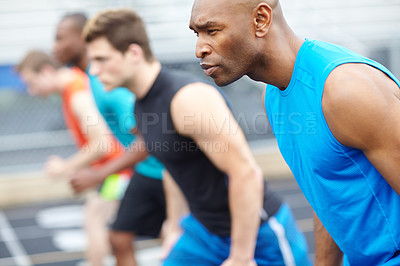 Buy stock photo Close up side view of a male runner in a line up of other athletes blurred in the background