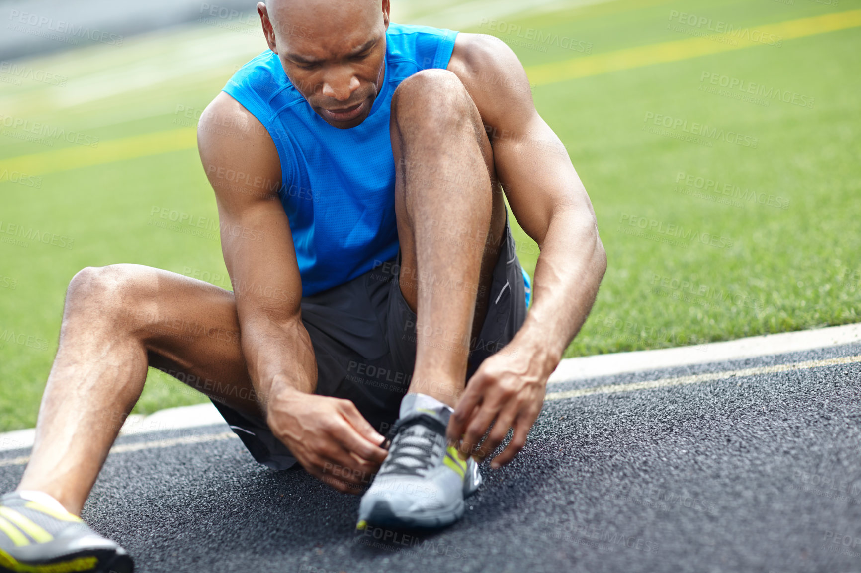 Buy stock photo Close up of a male athlete tying his shoelaces at the race track