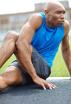 Buy stock photo Cropped shot of a male athlete stretching his leg muscles at the race track