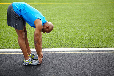 Buy stock photo Full length side view of a male athlete stretching at the race track