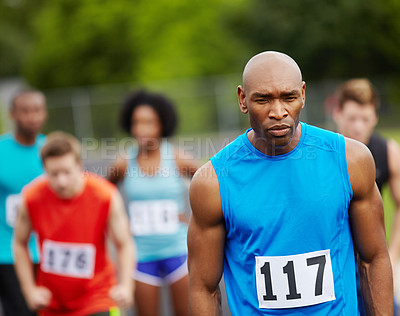 Buy stock photo Front view of a male runner looking determined at the beginning of the race with other athletes in the background