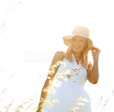 Buy stock photo A beautiful young blonde woman standing in a meadow wearing a sunhat on a summer's day