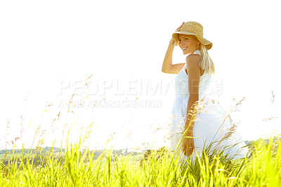 Buy stock photo An attractive young blonde woman standing in a meadow wearing a sunhat on a summer's day