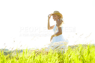 Buy stock photo A beautiful young blonde woman standing in a meadow wearing a sunhat on a warm summer's day