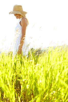 Buy stock photo An attractive young blonde woman standing in a meadow wearing a sunhat on a summer's day