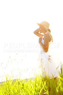 Buy stock photo An attractive young blonde woman standing in a meadow wearing a sunhat on a summer's day