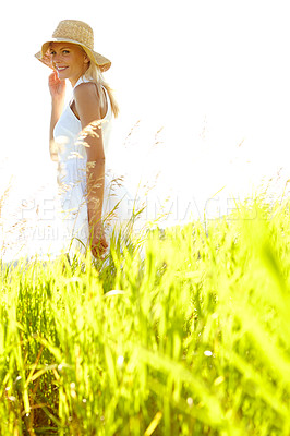 Buy stock photo An attractive young blonde woman standing in a meadow wearing a sunhat on a summer's day