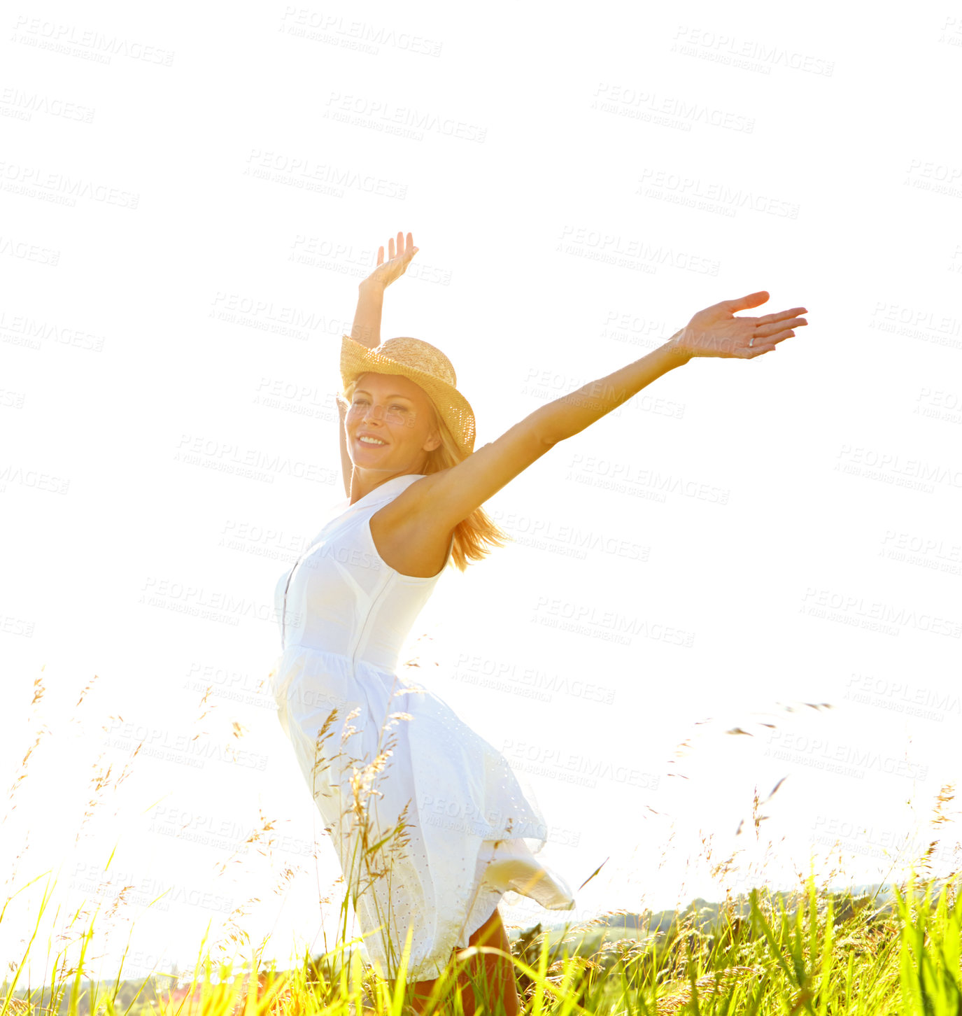 Buy stock photo A carefree young woman standing with her arms outstretched in a meadow while smiling blissfully