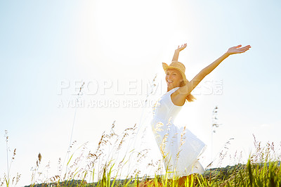 Buy stock photo A carefree young woman standing with her arms outstretched in a meadow while smiling blissfully