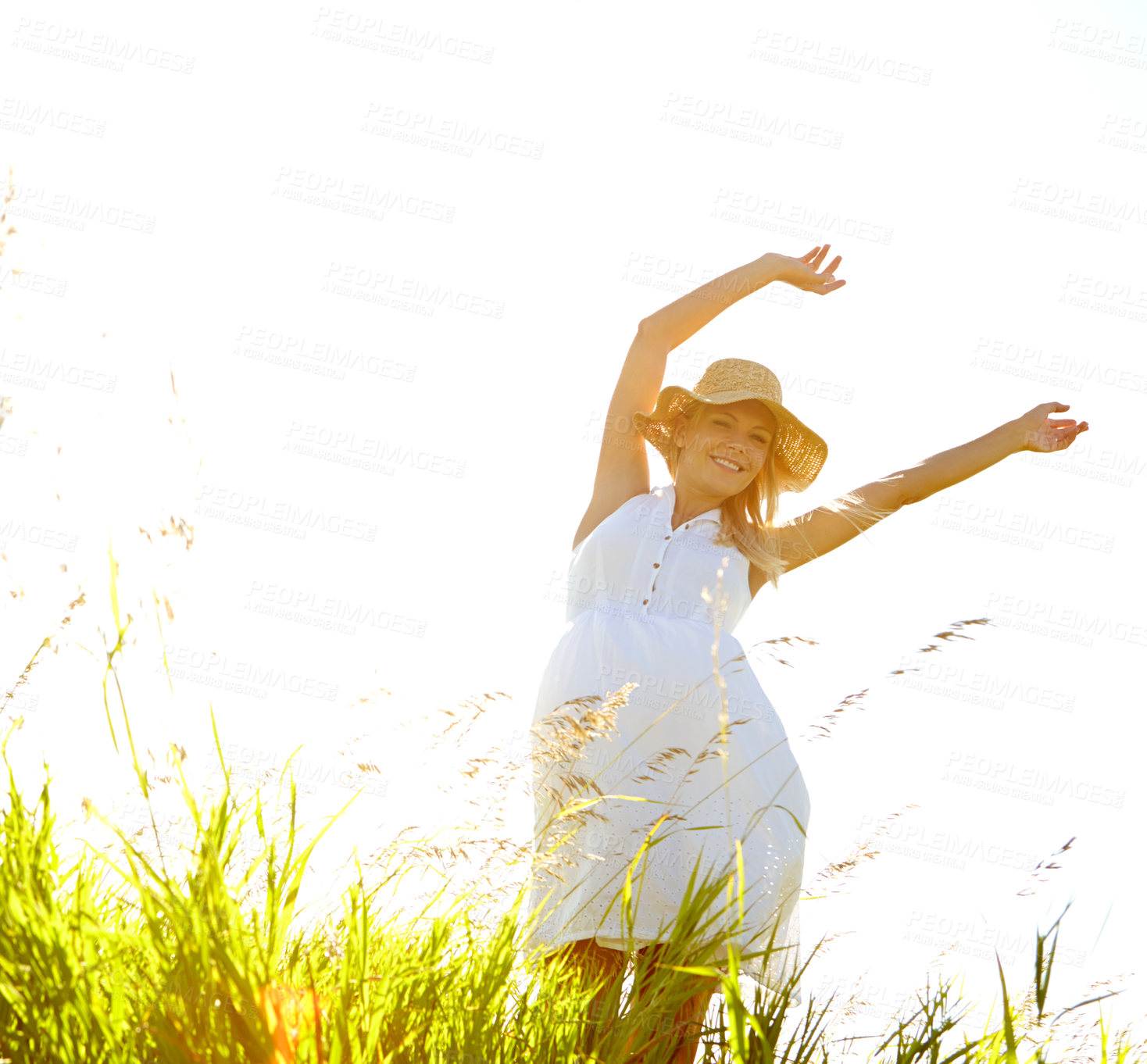 Buy stock photo A carefree young woman standing with her arms outstretched in a meadow while smiling blissfully