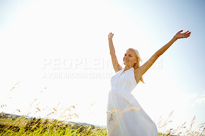 Buy stock photo A young woman in a field with her arms outstretched