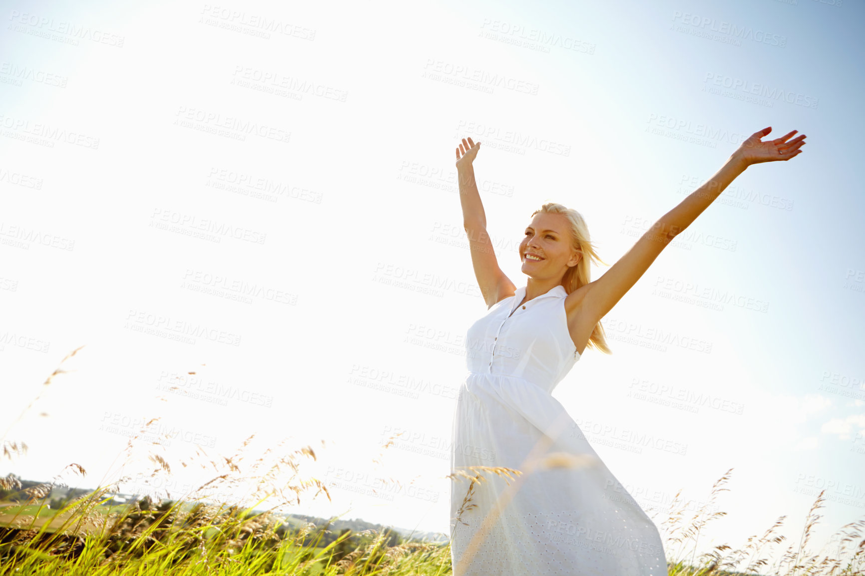 Buy stock photo A young woman in a field with her arms outstretched