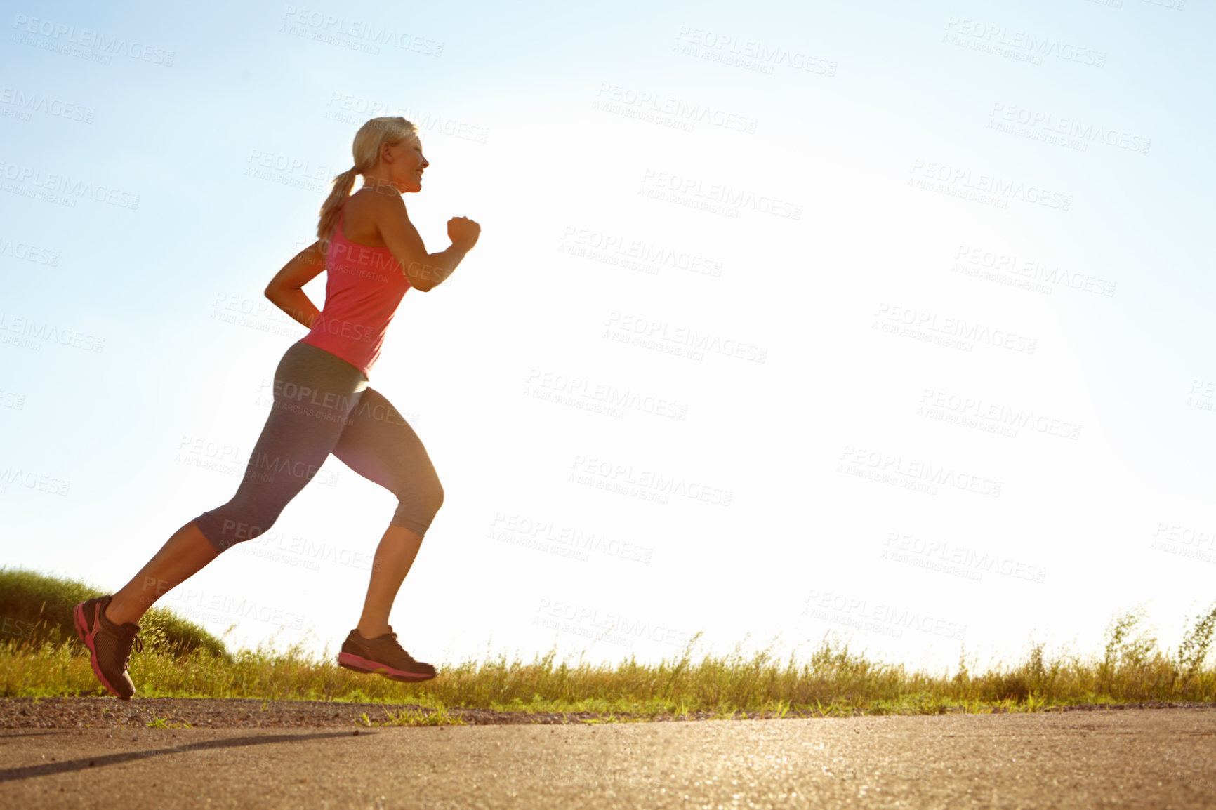 Buy stock photo Fitness, happy woman and running in nature space for cardio exercise, training and wellness. Below, athlete and sport at sky mockup for marathon preparation, endurance and uphill challenge at sunrise