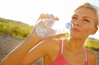 Buy stock photo A beautiful young woman in sportswear drinking water from a bottle